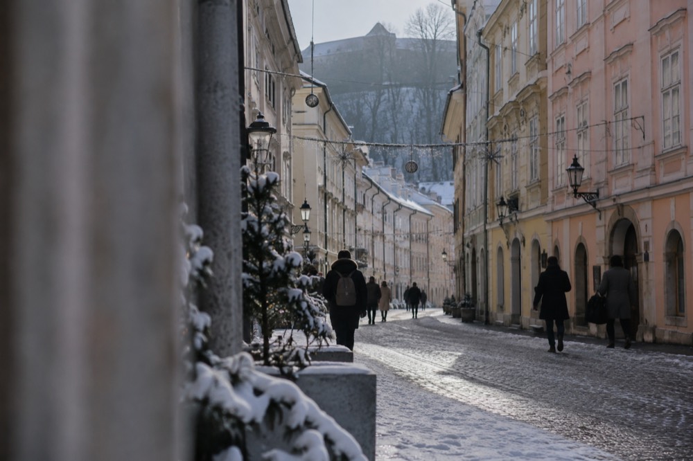 Fresh snow on the cobbles of a pedestrianised old town street with festive lights strung above