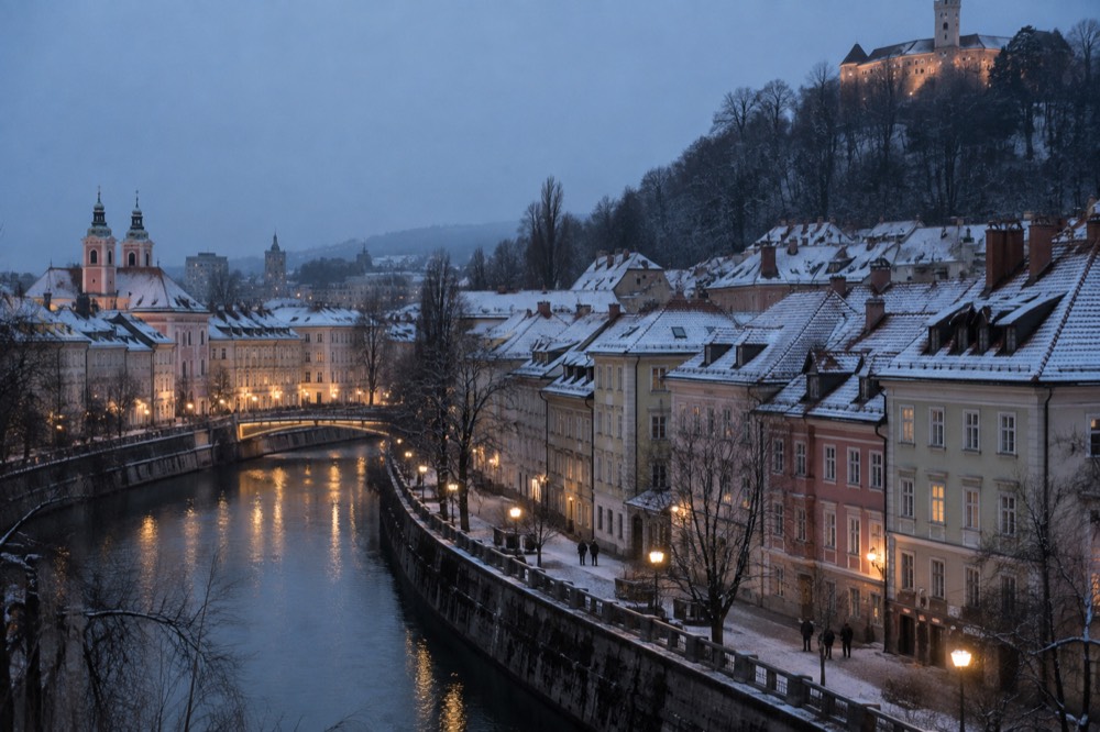 Snow-dusted rooftops of Ljubljana Old Town seen across the Ljubljanica river on a cold morning