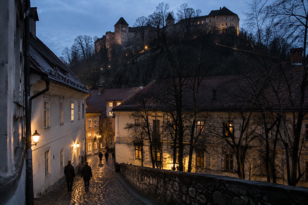 Evening lights reflecting on wet cobblestones in a quiet Ljubljana side street in winter