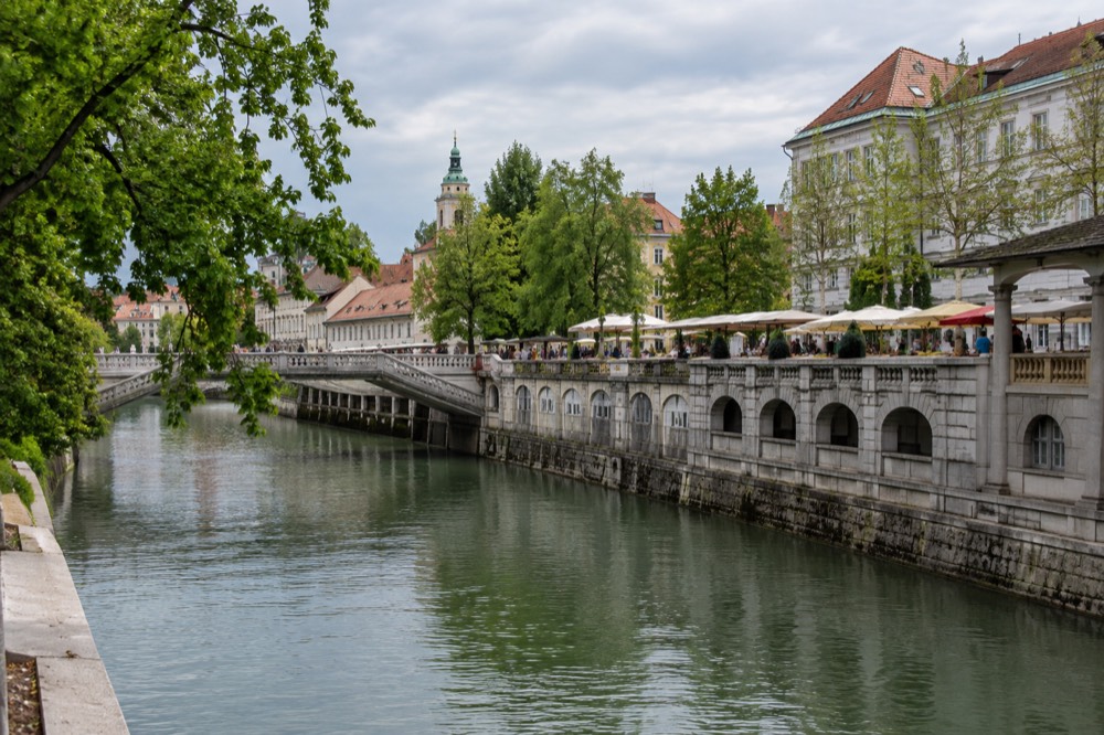 The riverside colonnade and bridges seen from the opposite bank of the Ljubljanica