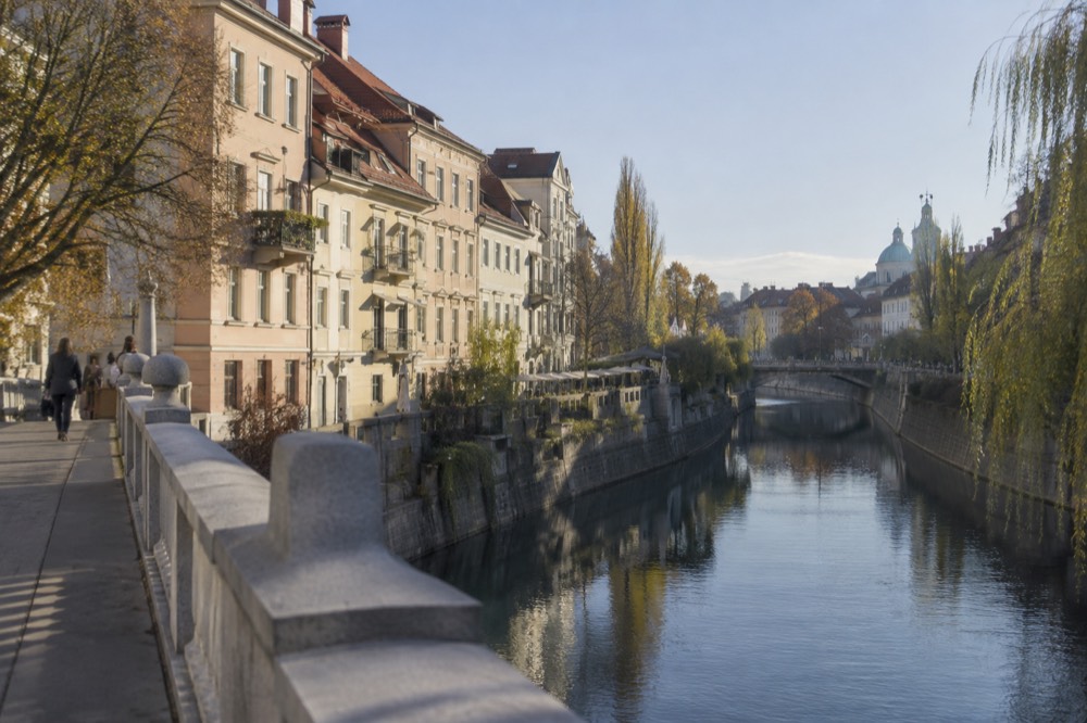 Pastel buildings beside the Ljubljanica river in Ljubljana on a bright morning
