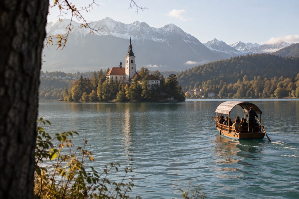 A wooden pletna boat crossing green lake water toward the small island with its church tower