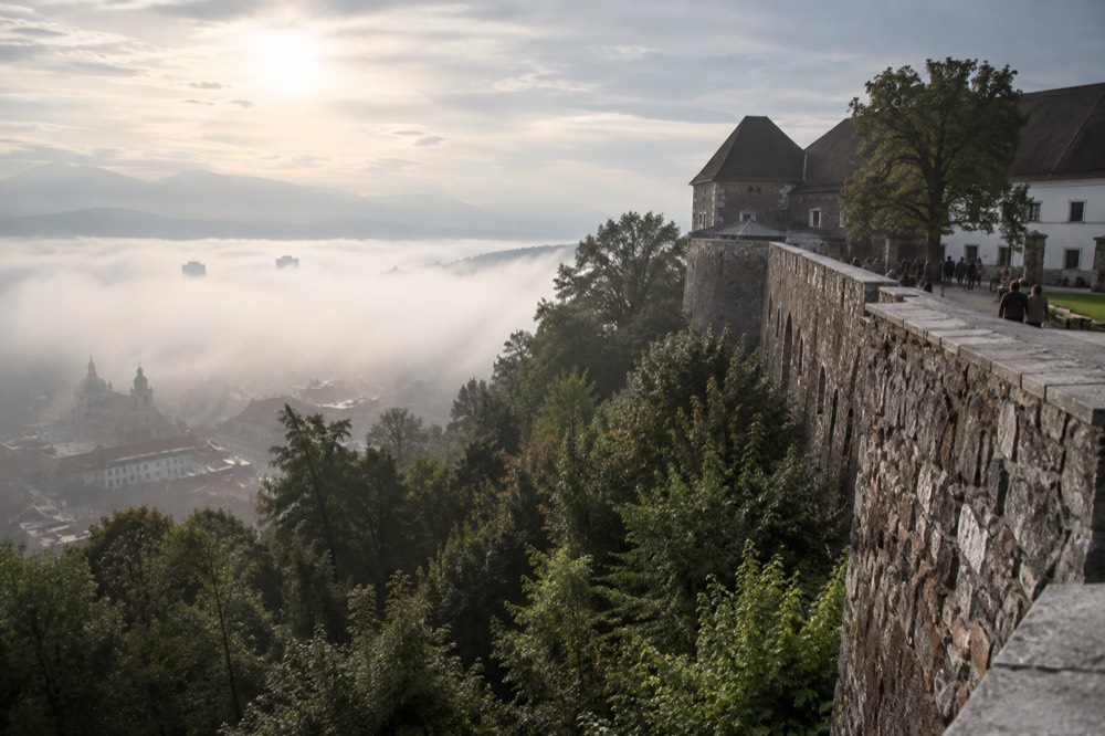 Morning fog sitting over the Ljubljana basin with the castle hill rising above the mist layer