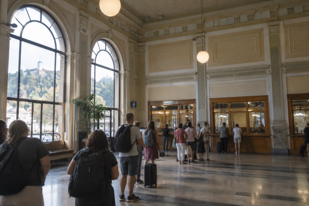 The ticket hall of Ljubljana Train Station with travellers queueing at the counters