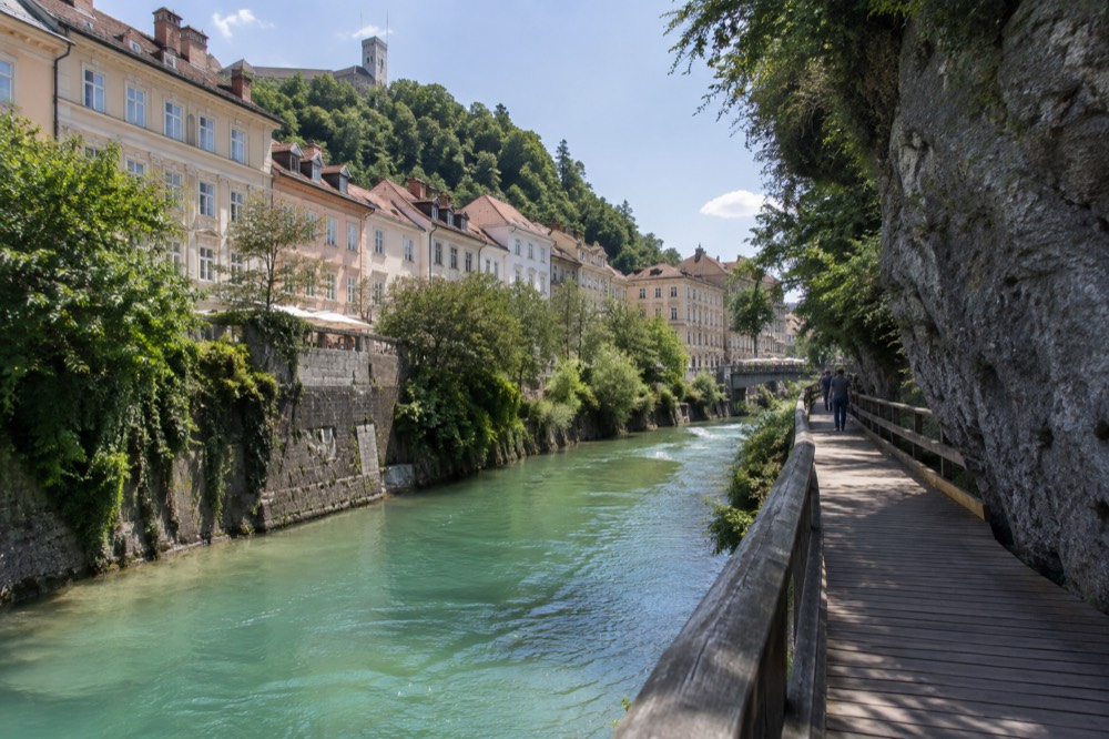 A wooden walkway curving along turquoise water in a gorge with high rock walls