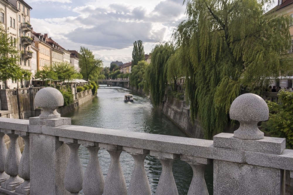 The stone balustrade and riverside trees of a bridge over the Ljubljanica