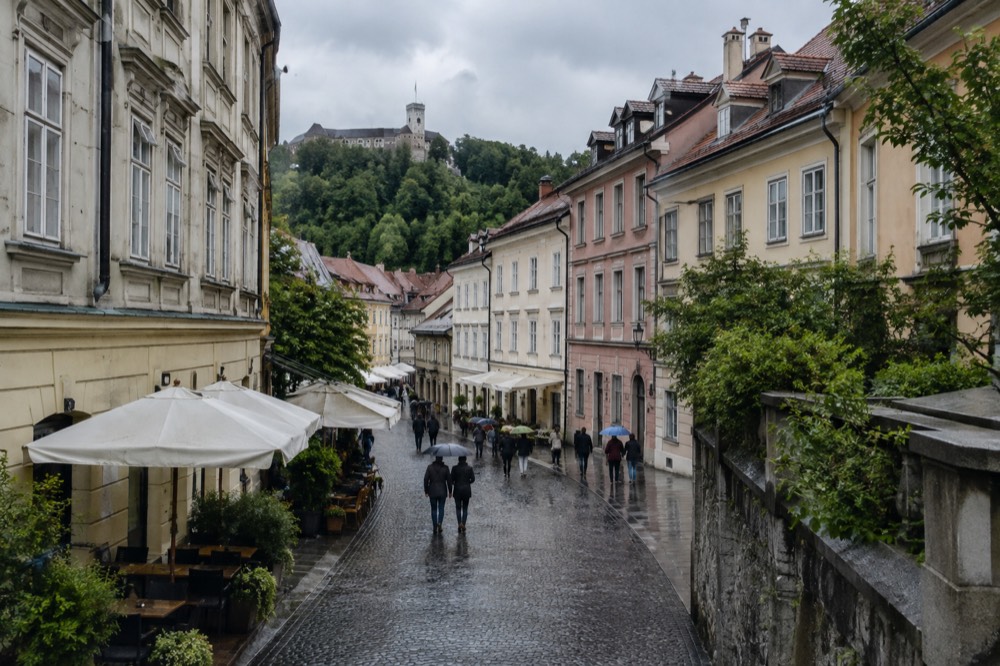 Rain-washed cobblestones in an old town street with market awnings and grey sky above