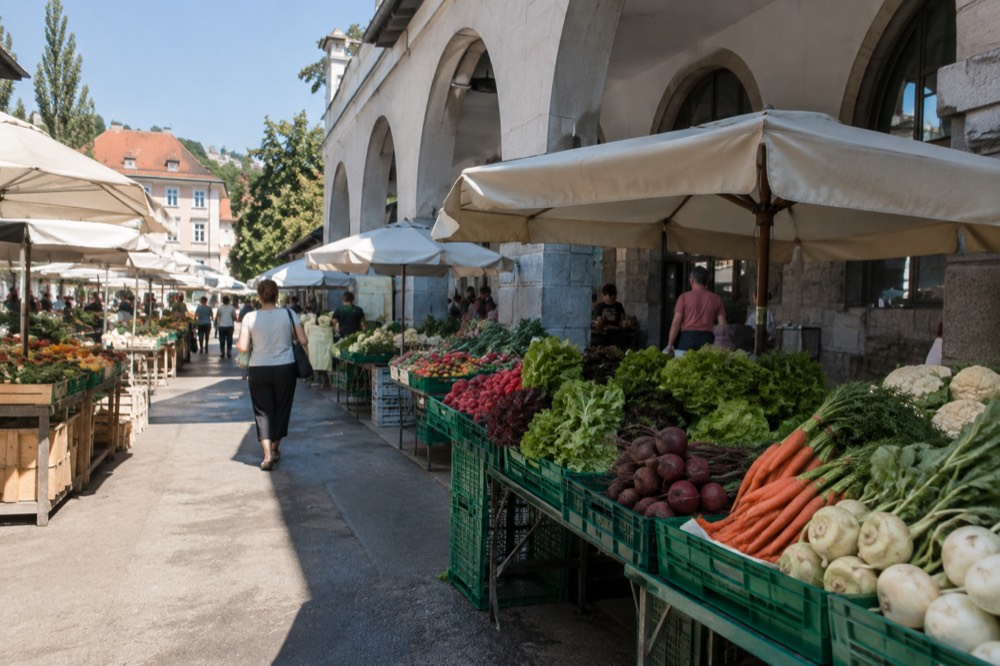 Market stalls of fresh produce under the stone arches of the Central Market colonnade