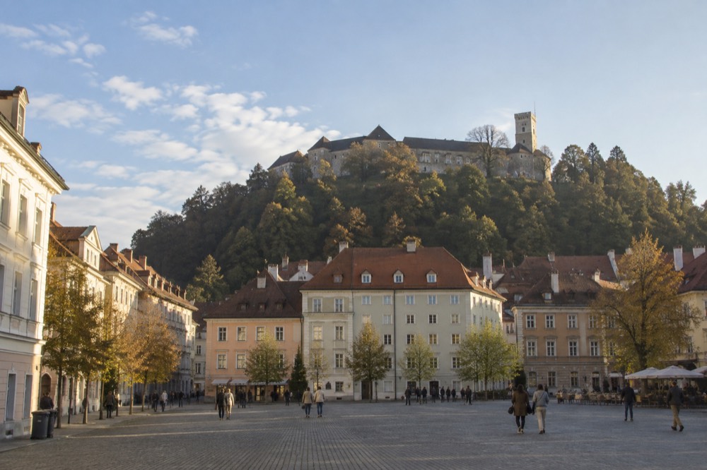 A wide car-free square in the city centre with the castle hill rising behind the rooftops