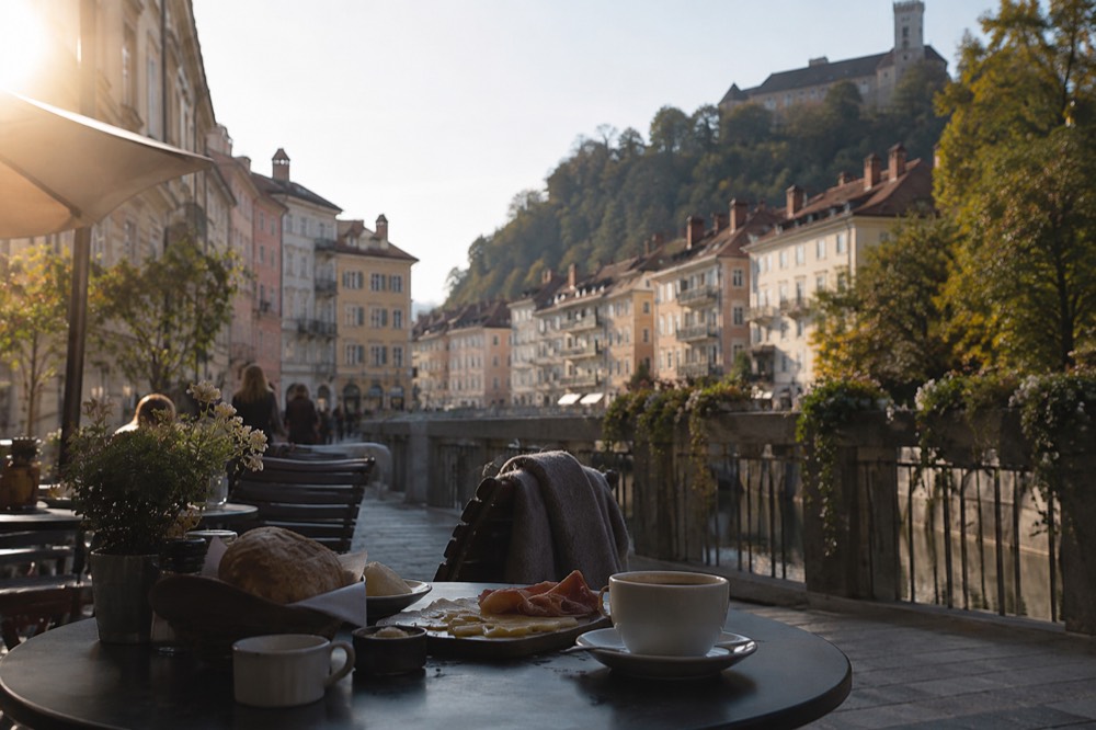 A breakfast table with bread, cheese, sliced meat and coffee on a cafe terrace