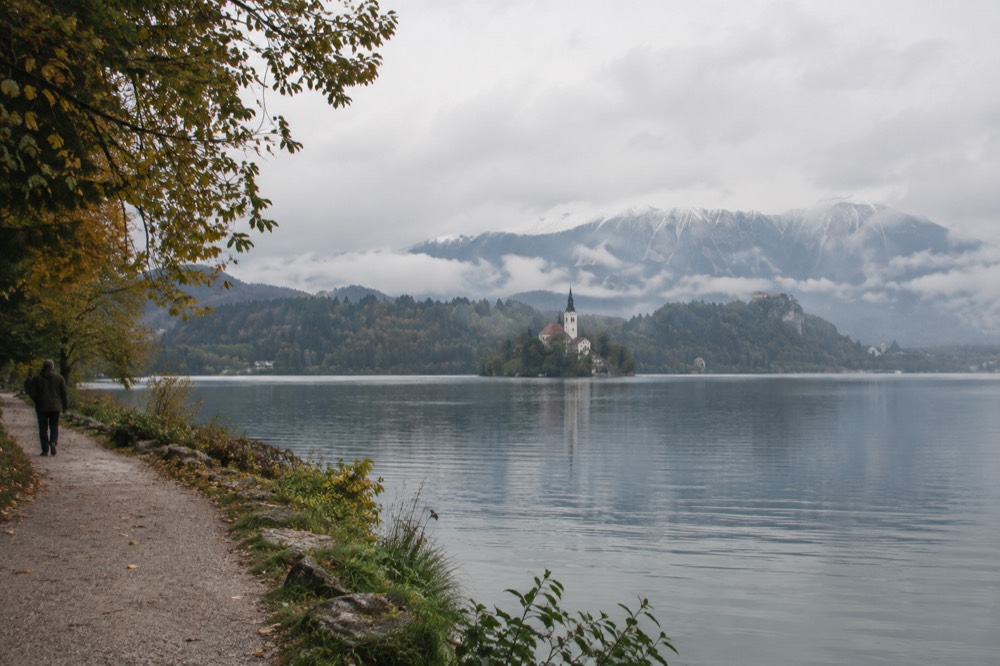 Walking path along the northern shore of Lake Bled with the Julian Alps behind