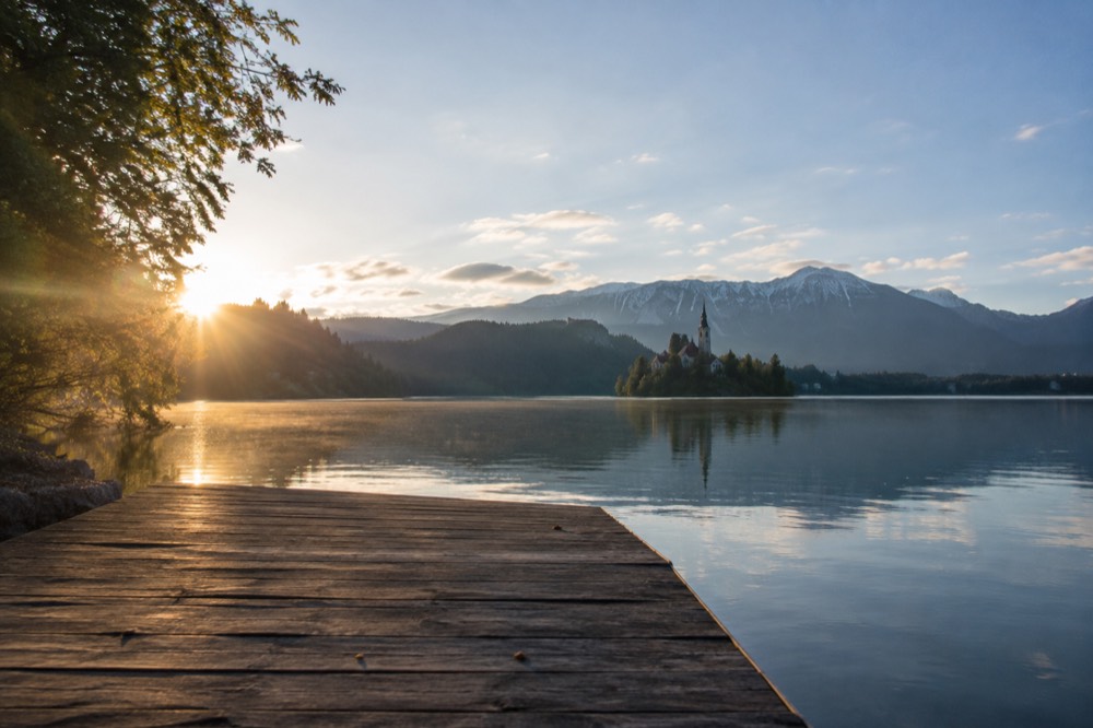 Empty wooden jetty on the quiet western shore of Lake Bled at dawn