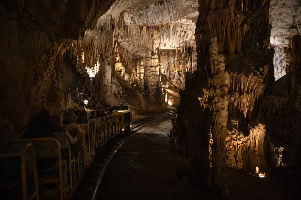 The cave train track winding into the illuminated galleries of Postojna Cave