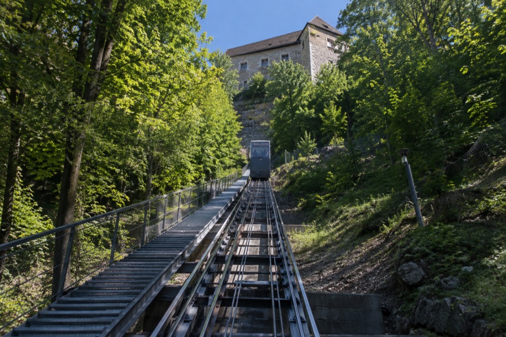 The funicular car climbing the wooded slope toward Ljubljana Castle's walls