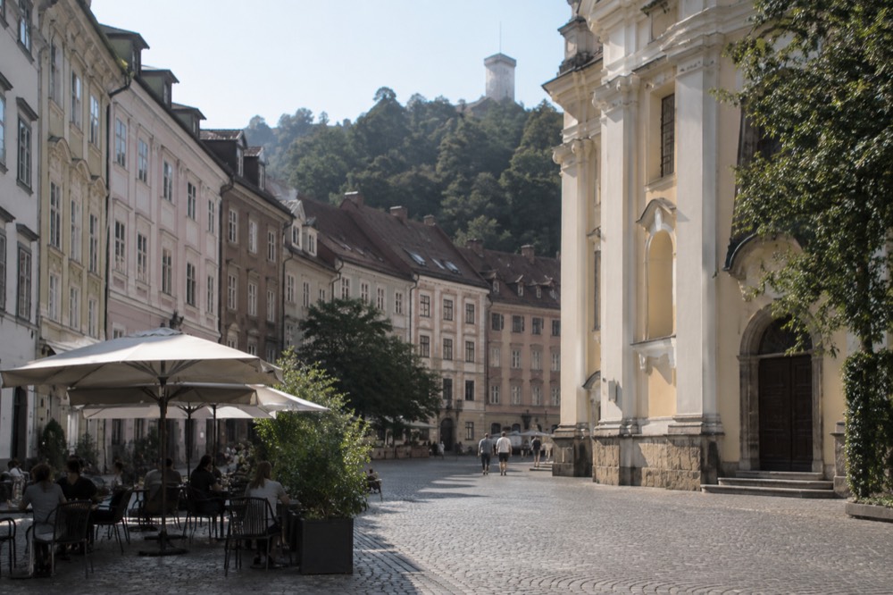 Cobbled square with church facades and cafe tables in morning light