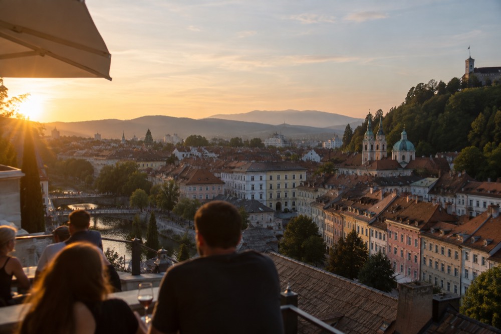Rooftops and green hills at sunset seen from a high terrace