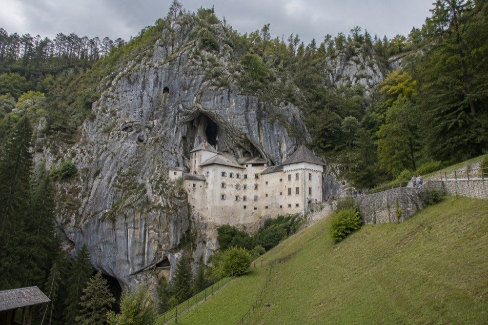 Predjama Castle built into a cliff face under a grey sky